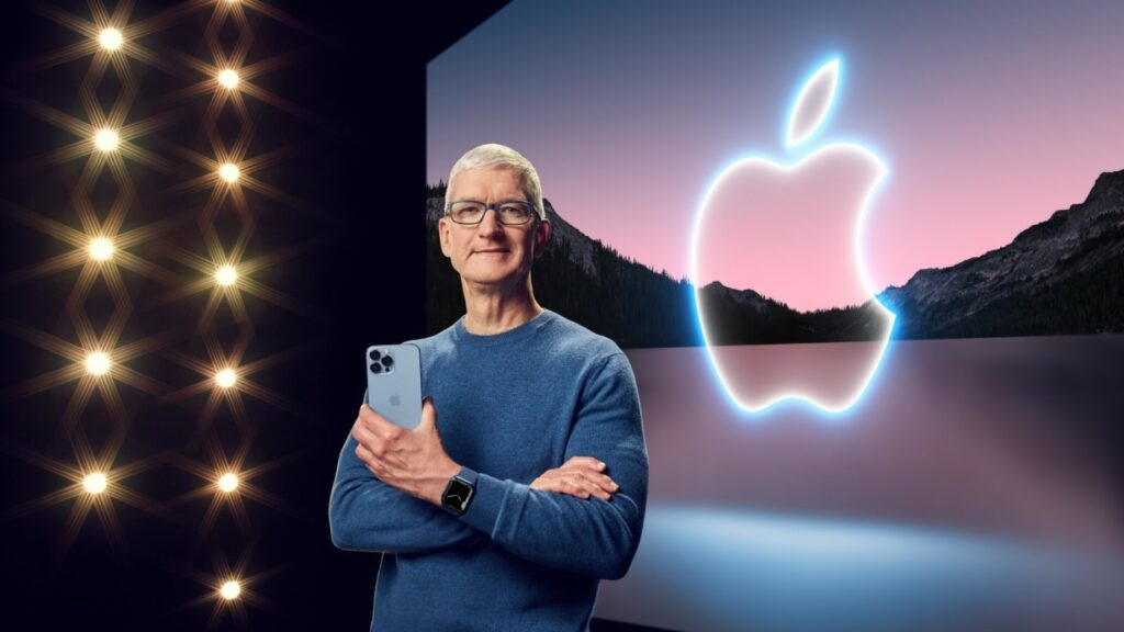 苹果首席执行官蒂姆·库克站在台上，手里拿着iPhone，戴着苹果手表